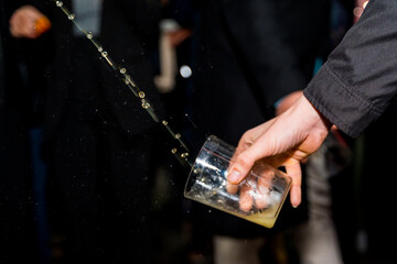 Hand holding a glass of apple cider at an event in a cider house, Basque Country