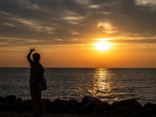 A woman waving v sign at a beach on the morning sunrise in Thailand