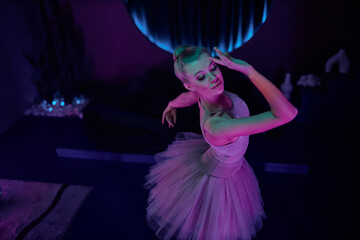 High angle shot of female ballet dancer posing in studio with gradient neon lighting