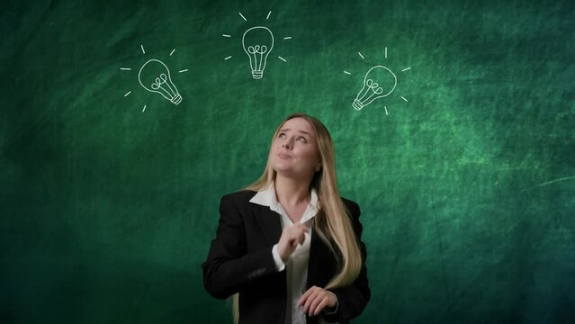 Portrait of woman isolated on green background light bulbs image on top. Girl standing looking up for a sign, guessing choosing solutions, lamp lights up.
