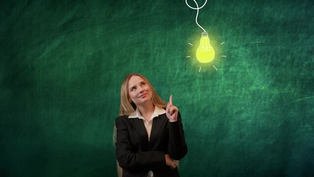 Portrait of woman isolated on green background light bulb image on top. Girl standing looking up having fresh idea raising finger up happily, lamp lights up.