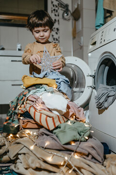 Boy making Christmas tree from heap of laundry clothes in bathroom