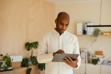 Confident businessman using digital tablet standing at home office
