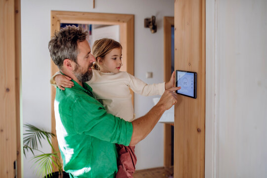 Father teaching daughter to adjust home automation app on tablet PC