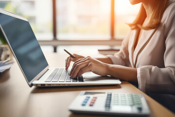 Closeup shot of businesswoman using a calculator and laptop in an office.