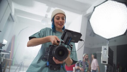 Young Professionals Working in Film Studio: Slow Motion Zoom in on a Female Professional Videographer Using Modern Equipment to Film a Creative Project. Crew of Film Students Filming School Project
