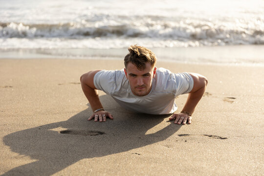 Man doing push-ups on sand at beach