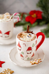 Winter hot chocolate with marshmallows in a mug with marshmallow snowman on a light background. Cozy still life with cocoa drink, cookies and decorations, gingerbread cookies, fir and poinsettia.