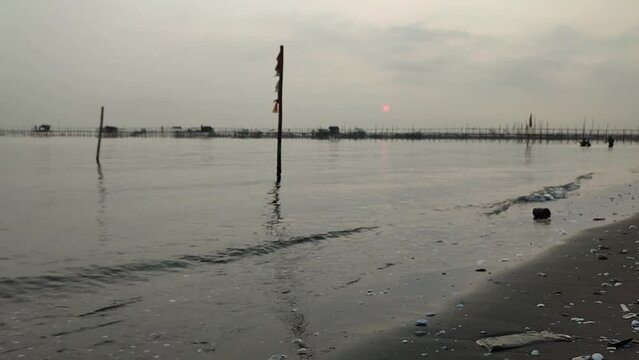 Small beach waves with sunrise blur background and fishing spot, summer vacation on tropical beach of Tanjung Kait.