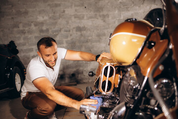 A man dusts off his retro motorcycle in the garage