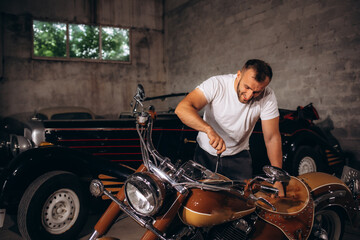 A man repairs a retro motorcycle in the garage
