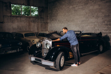 A man repairs a retro car in the garage