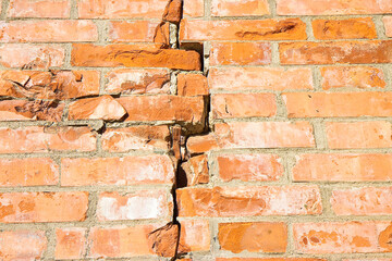 Old brick wall cracked and damaged due to structural failure, subsidence or damage from earthquake