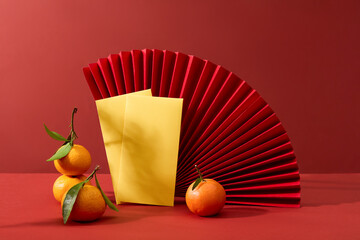 A large handmade paper fan featured over red background with envelopes and tangerines. The Chinese...