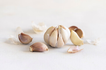Fresh whole bulb of garlic and cloves on a white table close up