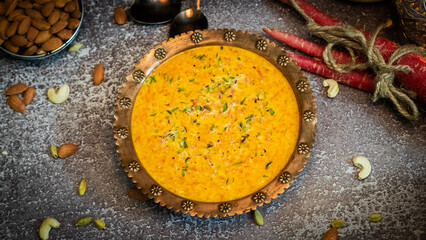 Carrot Kheer or payasam also known as Gajar ki Khir in a bowl with brown textured background and...