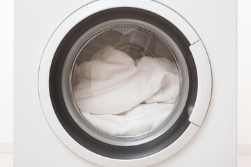 Closed washing machine full of white clothes. Closeup. Front view.