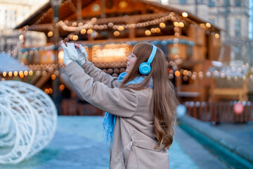 smiling young woman  having a fun time in Christmas market , using phones at outdoor in urban city. people, communication,  shopping and lifestyle concept