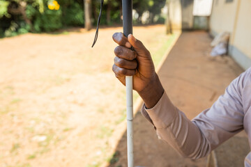 Close-up of the right hand of a blind person holding a white cane
