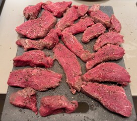 Raw slices of Tenderloin with spices and herbs being prepared to be grilled