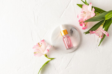 Fashion beauty product, oil or serum in glass cosmetic bottle with dropper for face and body skin care lies on a round marble podium. Top view.