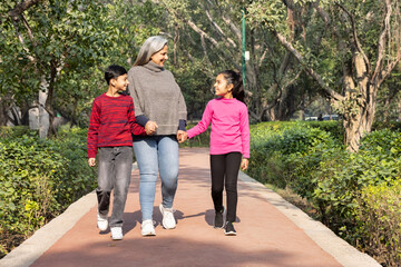 Obraz premium Happy grandmother walking with grand children at park