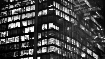 Obraz premium Pattern of office buildings windows illuminated at night. Glass architecture ,corporate building at night - business concept. Black and white.