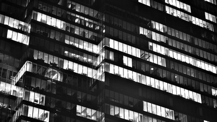 Obraz premium Pattern of office buildings windows illuminated at night. Glass architecture ,corporate building at night - business concept. Black and white.