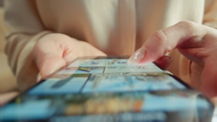 Unrecognizable woman choosing online games in app store on smartphone. Close-up shot of girl in blouse using game platform on device. Female hands touching screen of mobile phone, scrolling
