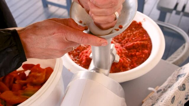 Grind red peppers in an electric meat grinder. Selective focus.