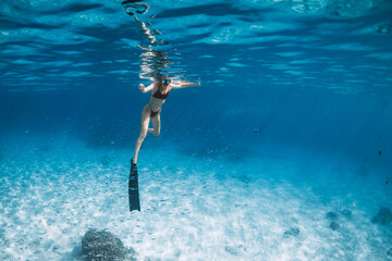 Woman with fins swimming over sandy sea. Free diver in blue ocean in Hawaii