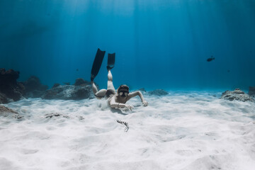 Woman free diver and venomous sea snake in tropical blue ocean