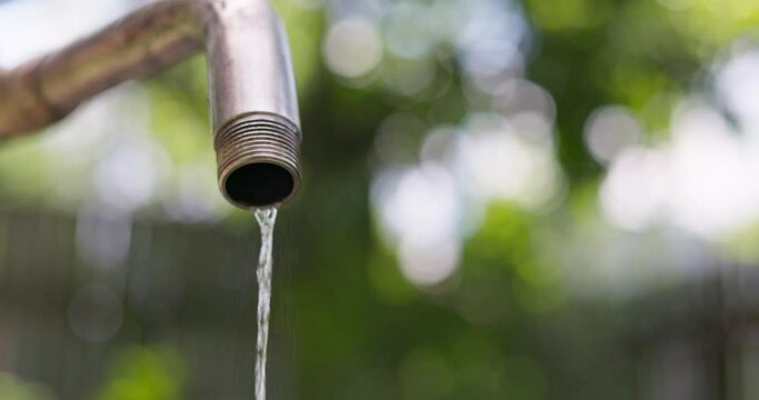 Water pouring from faucet outdoors. Wasting water. Shortage of water concept