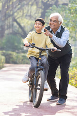 Boy learning bicycle with assistance of grandfather at park
