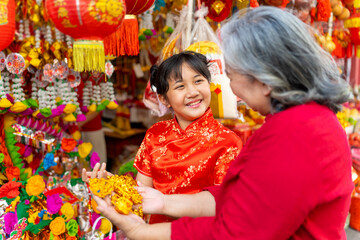 Happy Asian family grandmother and grandchild girl in red dress choosing and buying home decorative...