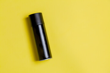 Black spray can isolated on yellow background. Mockup. Can concept. Beauty product concept. Space for text. Mockup.