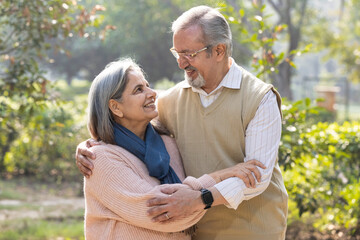 Portrait of Indian senior couple embracing while standing in park.