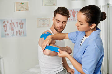 Obraz premium good looking man sitting and watching his young doctor putting kinesio tape on his elbow, healthcare