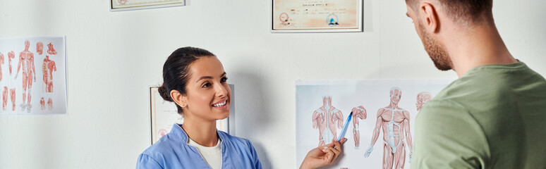 joyous doctor in medical costume showing anatomy schemes to her patient, healthcare, banner