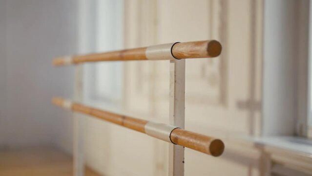 Wooden ballet barre in dance studio. Equipment for dance, classical ballet training workout, practicing dance elements, exercising in gym school theatre. Two wood sticks handrails connected by metal.