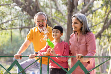 Grandparents, bubbles and children play in park happy together for fun