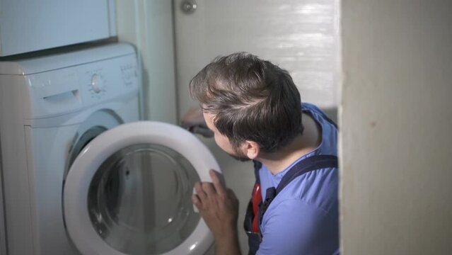 man a repairman repairs the washing machine at home
