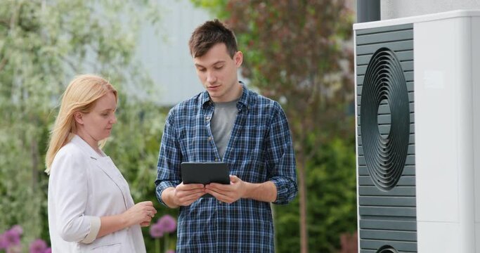 A young engineer advises a client in setting up a heat pump
