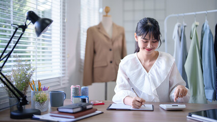 Young asian merchant women using calculator to calculate about financial of online shopping...