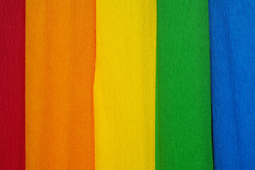 Rolls of crepe paper lying next to each other in the colors red, orange, yellow, green and blue