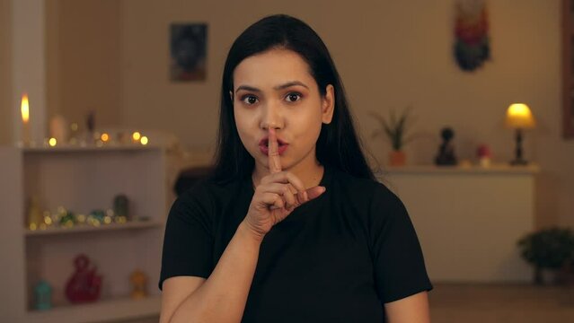 4K stock footage: portrait of a lady shushing with a finger on her lips - silence  secret  eyeball movement . A beautiful Indian lady making a keep quiet gesture for the audience - eye exercise  de...