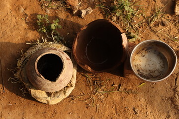 Small clay pots or matka and steel bowl filled with water outside on ground for animals and birds, top view - obrazy, fototapety, plakaty