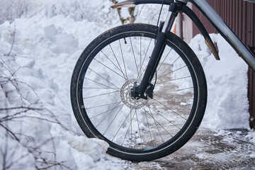 A bicycle wheel bumped into a snowdrift. Summer sports and winter. Inability to ride a bike