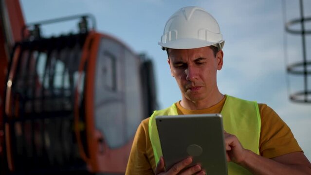 Industry concept. heavy industry engineer in working uniform in a hard hat with tablet.an engineer is working on tablet to develop new project.engineer in a hard hat works with construction equipment