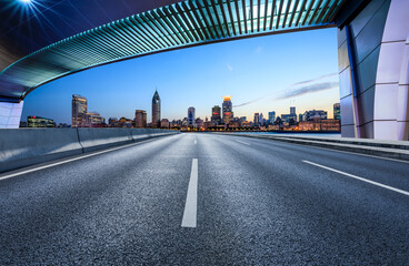 Asphalt road and bridge with modern buildings at dusk in Shanghai